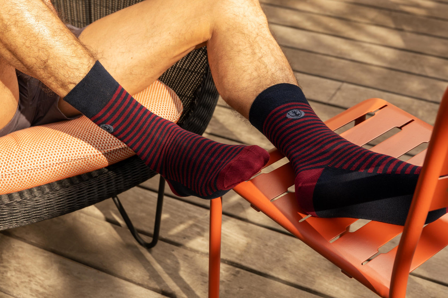 Chaussettes rayées Mariner en rouge et bleu, portées sur une chaise extérieure, parfaites pour un look confortable et élégant.