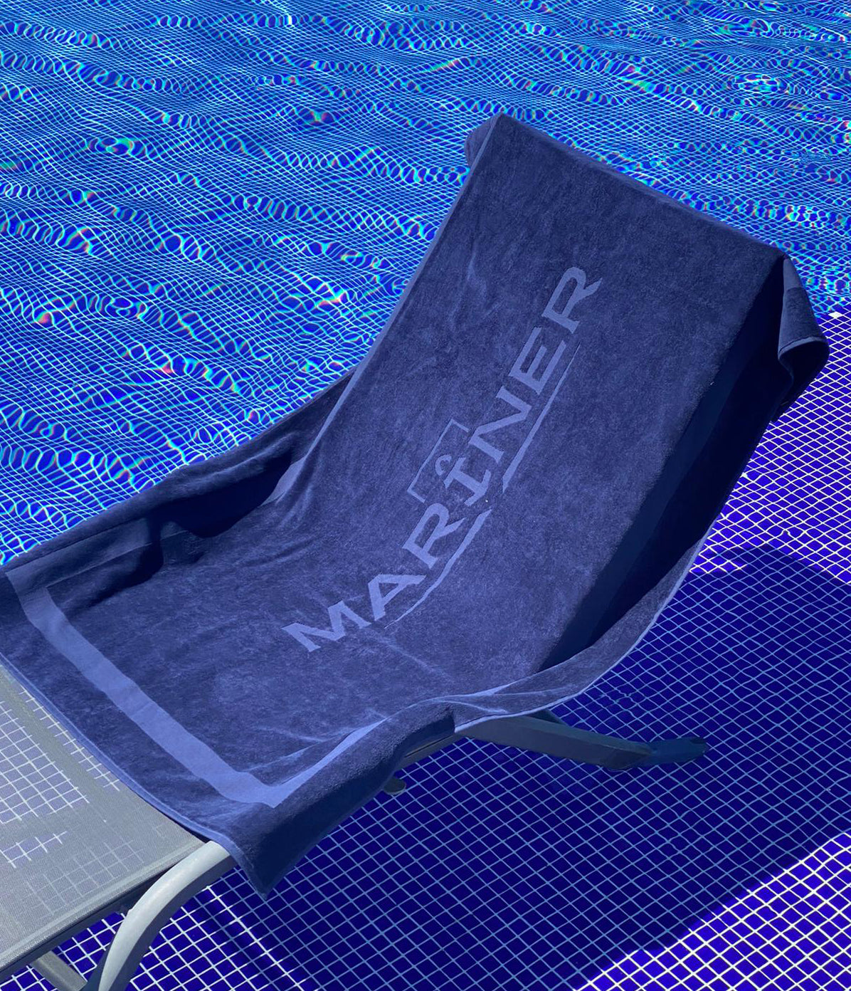 un drap de bain bleu foncé avec le logo "MARINER" imprimé dessus